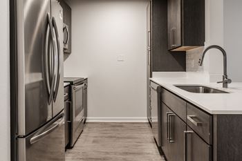 An empty kitchen with stainless steel appliances and a sink